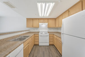 Interior Unit Kitchen, Granite-like Countertops, white appliances, refrigerator, light brown cabinetry, wood like floors.