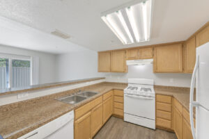 Interior Unit Kitchen, Granite-like Countertops, white appliances, refrigerator, light brown cabinetry, wood like floors.