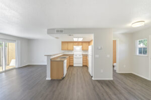 Unit Kitchen/Living Room, open floor plan, stairs leading to bedroom, white appliances, granite like countertops, wood like floors, white walls, dual sink.