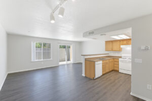 Unit Kitchen/Living Room, open floor plan, stairs leading to bedroom, white appliances, granite like countertops, wood like floors, white walls, dual sink.